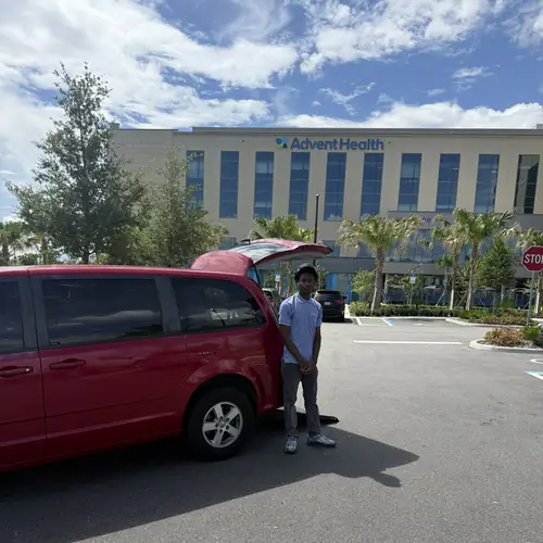 Red wheelchair accessible minivan with its rear ramp lowered in the AdventHealth Ocala parking lot