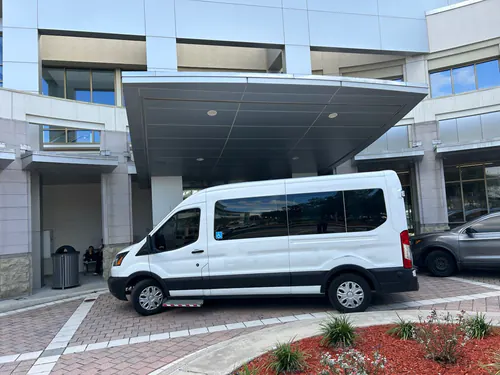 White high roof wheelchair accessible Ford Transit van at a covered hospital entrance near Mount Dora