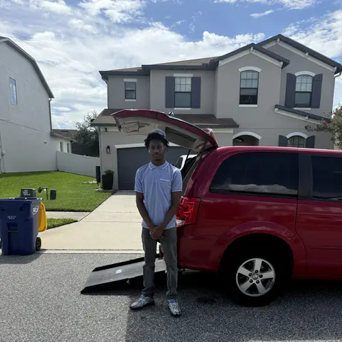 Red wheelchair accessible minivan with the rear ramp lowered to the street outside a Gainesville home