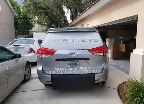 Back of a silver Comfort Ride Transportation Toyota Sienna showing the phone number and Non Emergency Medical Transportation lettering in an Ocala driveway