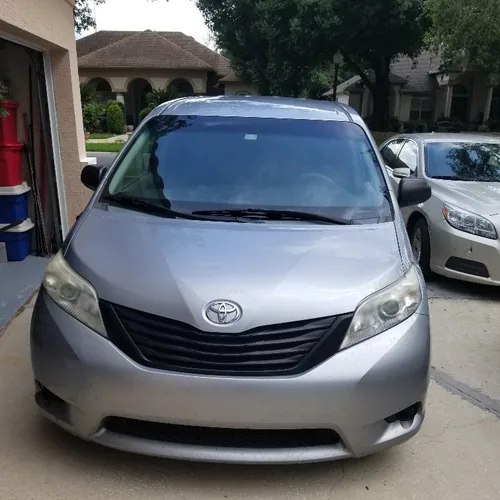 Front of a silver Comfort Ride Transportation Toyota Sienna parked in a residential driveway in Ocala