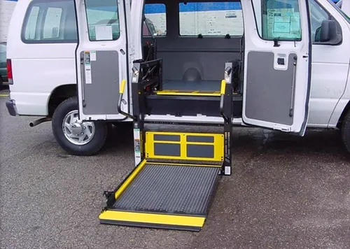 White wheelchair van with rear doors open and its yellow platform lift lowered to the pavement